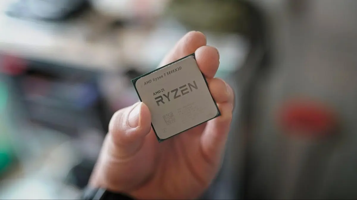 Mão segurando um processador AMD Ryzen 7 5800X3D, com fundo desfocado