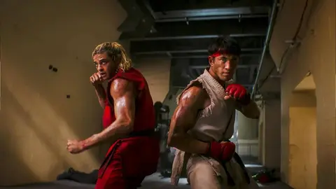 Atores caracterizados como Ken e Ryu, de Street Fighter, em cena de corredor com luz quente