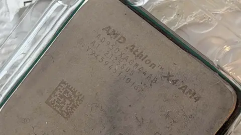Processador AMD Athlon X4 AM4 em close, sobre plástico transparente, com gravações na tampa metálica