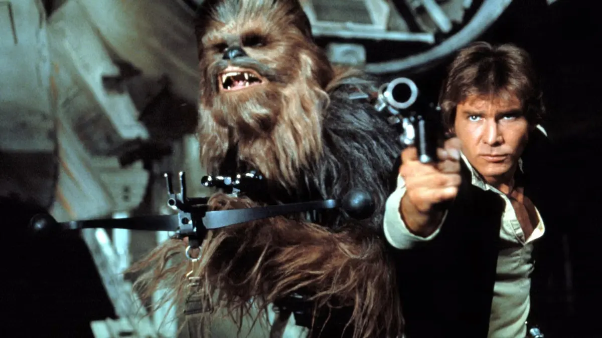 Han Solo aponta um blaster e Chewbacca ao lado dentro de uma nave, cena do filme Star Wars