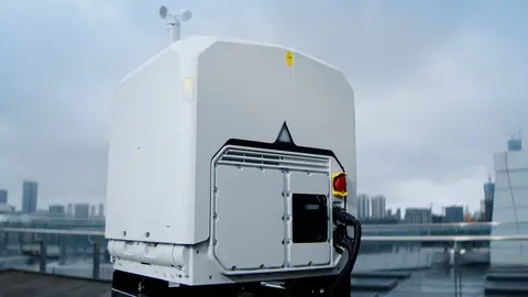 Estação externa branca com sensor meteorológico no topo, instalada em terraço com prédios ao fundo