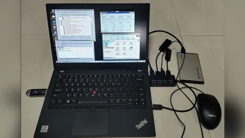 Notebook ThinkPad com Windows 98 SE na tela, ligado a hub USB, SSD externo e mouse, sobre piso claro