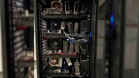 Rack aberto com placas de vídeo montadas sobre placas-mãe, fans e cabos, em ambiente de servidor caseiro