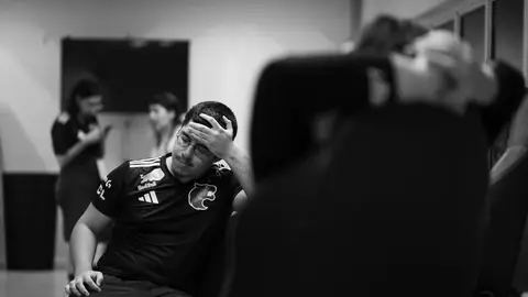 Jogador da FURIA de camisa preta com o logo da pantera, de mão na testa, em bastidores, foto em preto e branco