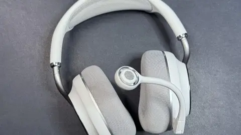 Headset sem fio branco de over-ear com microfone de haste destacável sobre superfície cinza