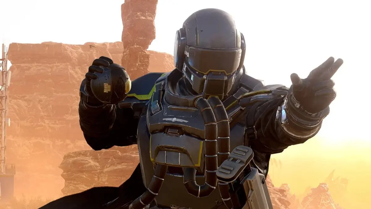 Soldado com armadura escura de Helldivers 2 segura um granada e aponta, em cenário de cânion desértico
