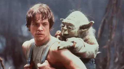 Luke Skywalker e Yoda em cena de Star Wars, numa floresta com neblina