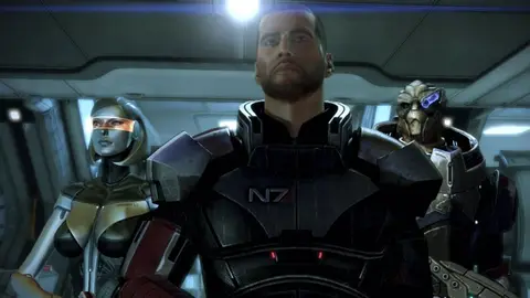 Shepard com armadura N7 no centro, ladeado por dois companheiros de equipe em nave, em cena de Mass Effect 3