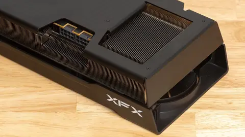Placa de vídeo Radeon XFX vista de trás, com dissipador de aletas e conector de energia de 8 pinos, sobre mesa de madeira