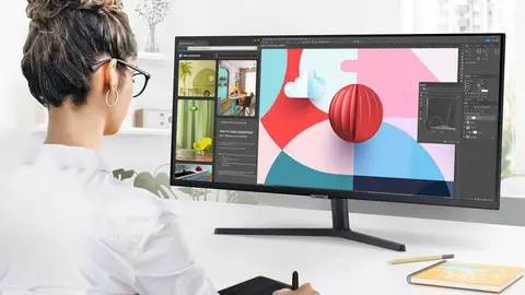 Mulher de camisa branca usa monitor ultrawide preto com software de design em mesa com mesa digitalizadora