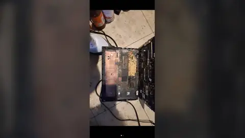 Notebook aberto no chão de cerâmica, com restos de insetos e sujeira acumulados sobre a placa interna