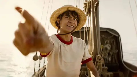 Personagem Luffy de One Piece com chapéu de palha, sorrindo e apontando em um navio no mar