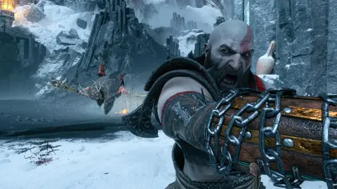 Kratos em cena de God of War, com correntes presas ao braço e um inimigo caído na neve ao fundo
