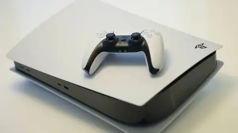 Console PlayStation 5 branco com controle DualSense preto e branco sobre a carcaça, em fundo claro