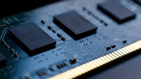 Close-up de módulo de memória RAM, com chips pretos e contatos dourados sobre placa de circuito azul