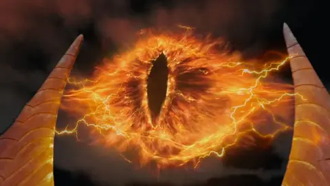 Olho de Sauron em chamas, com chifres negros dos dois lados, contra céu escuro de O Senhor dos Anéis