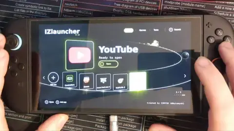 Console portátil preto nas mãos de uma pessoa, com o launcher IZlauncher mostrando o aplicativo YouTube pronto para abrir