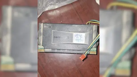 Módulo Pentium II Slot 1 da Intel, preto, com fios coloridos presos à lateral, sobre mesa de madeira escura