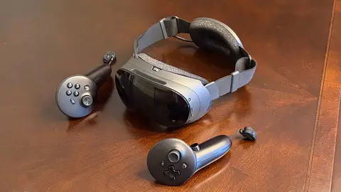 Headset Steam Frame da Valve ao lado de dois controles sobre uma mesa de madeira