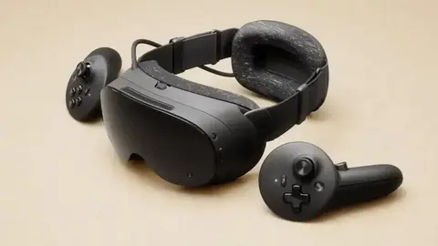 Headset de realidade virtual preto com dois controles sobre fundo bege, em foto de estúdio