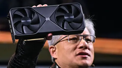 Homem de óculos segurando uma placa de vídeo Nvidia GeForce RTX de dois ventiladores em evento ao vivo