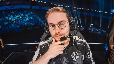 Jogador de e-sports com headset e camisa de equipe com logo de leão, em arena com plateia ao fundo