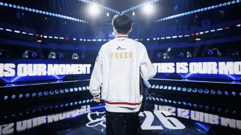 Faker de costas, com jaqueta branca da SK Telecom, caminhando em palco de evento de League of Legends