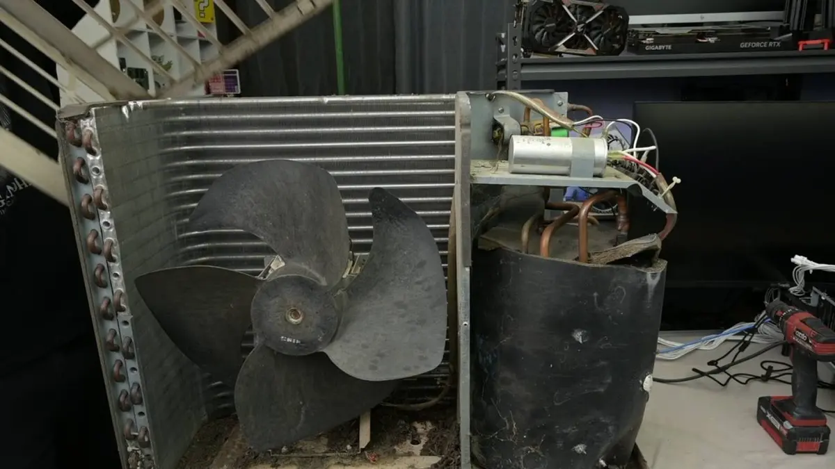 Radiador de ar-condicionado com ventilador de pás pretas em oficina, com placa de vídeo GeForce RTX ao fundo